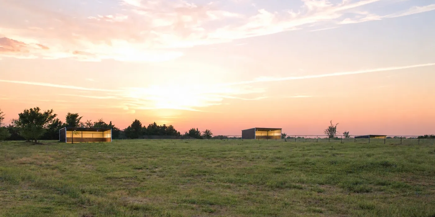 Open pasture at Franklin Farm at sunset, with run-in shelters along the fence line.