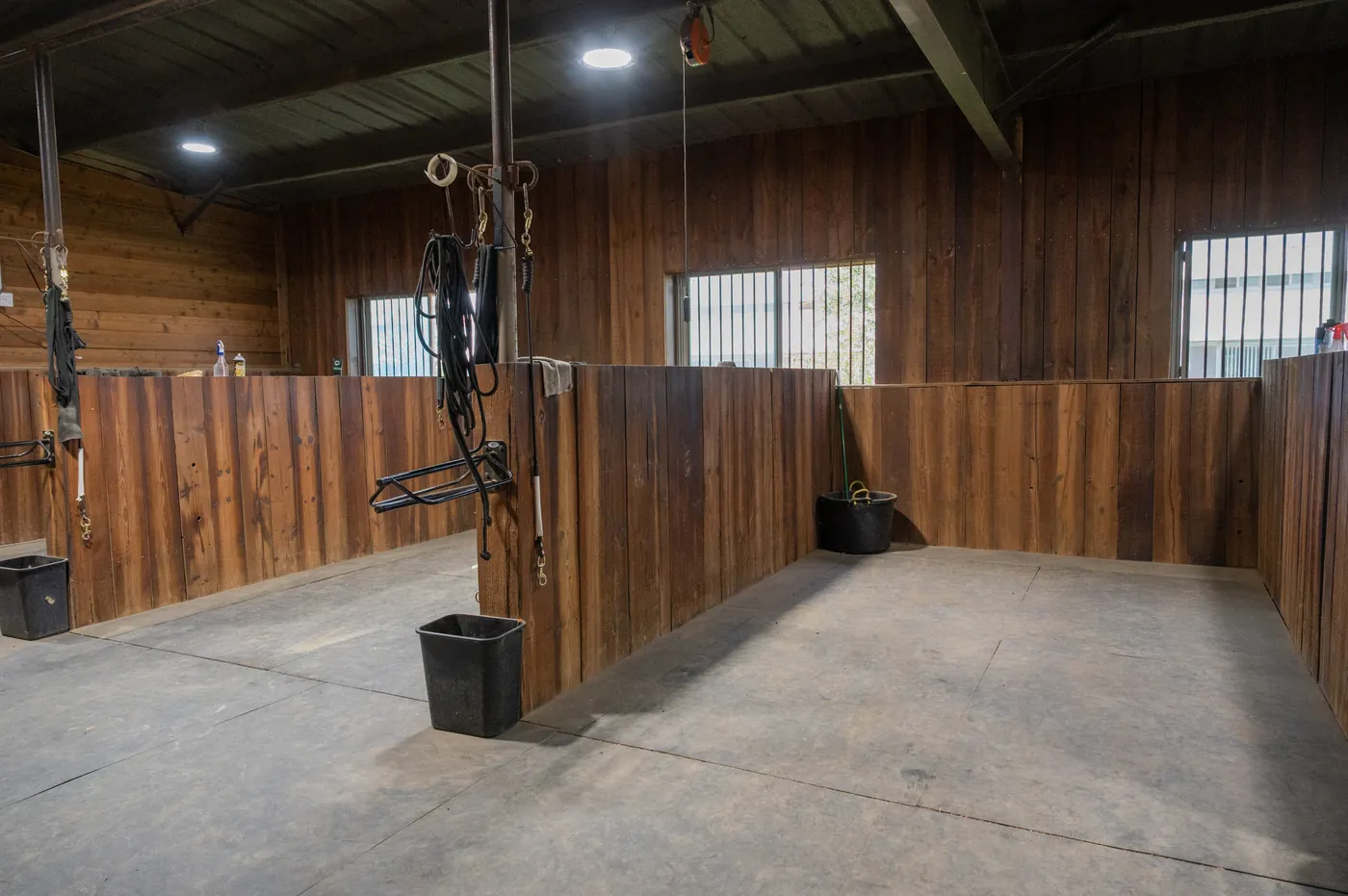 Wood-lined tie stalls at Franklin Farm, with cross-ties and tack hanging ready along the partitions.