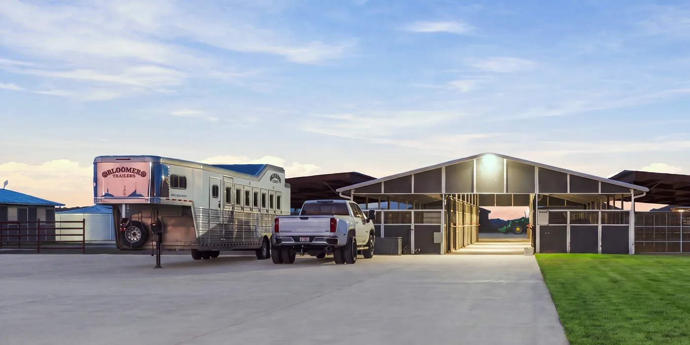 A truck and horse trailer parked beside the covered barn at Franklin Farm at dusk.