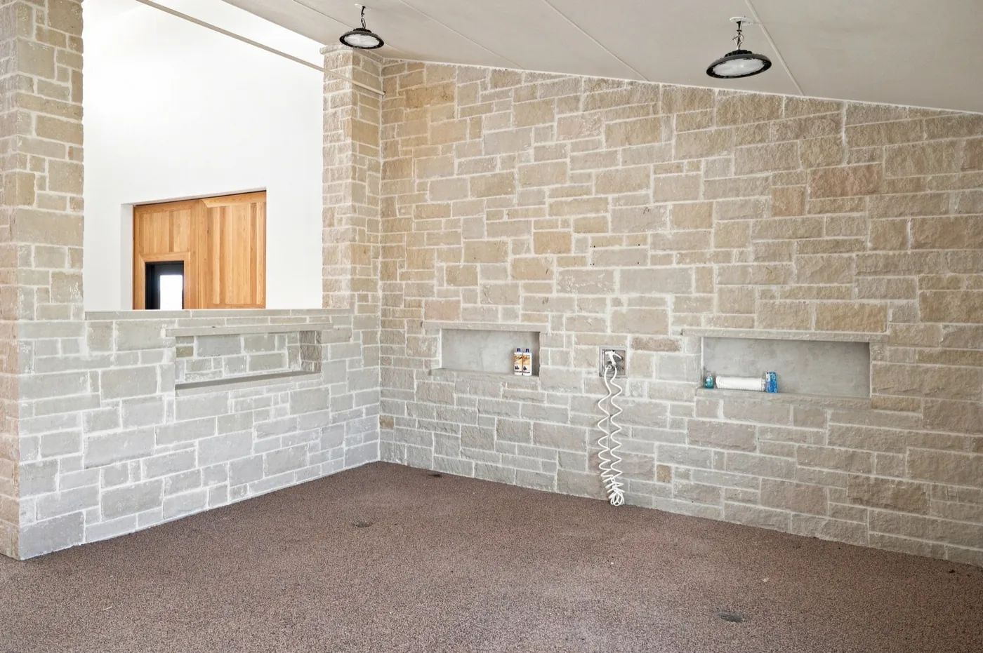 A stone wash stall at Franklin Farm, with recessed shelving and a coiled hose.